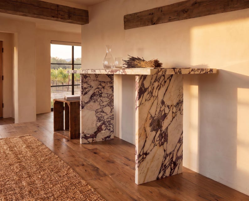 May include: A rectangular console table crafted from white marble with prominent deep purple veining. The table features a flat top supported by two vertical slab legs, showcasing a continuous stone pattern throughout the entire structure.