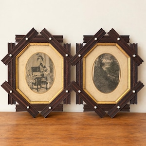 May include: Two matching octagonal wall frames with dark brown ridged wood borders, gold inner trim, and small white circular accents. Each frame contains a black and white oval print, one depicting a person with a plant and one a landscape.