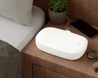 May include: A white, oval-shaped, portable UV light sanitising case with a smooth, matte finish and a small square power indicator light on the top lid, connected to a thin white power cord extending from the back of the device.