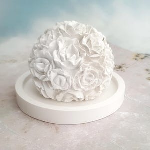 Könnte beinhalten: Ein weißer Keramikblumenstrauß mit runder Basis. Der Strauß besteht aus vielen kleinen, detaillierten Rosen.
