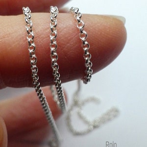 May include: Three silver rolo chains of different thicknesses, shown on a finger. The chains are made of 925 sterling silver.