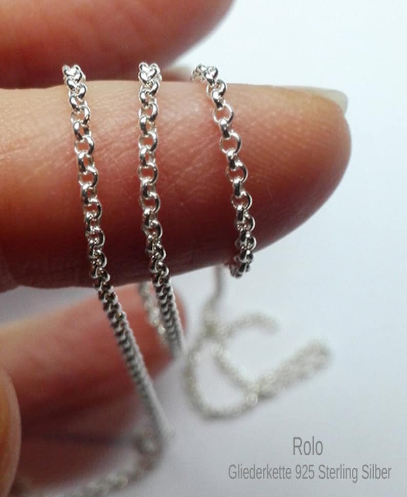 May include: Three silver rolo chains of different thicknesses, shown on a finger. The chains are made of 925 sterling silver.