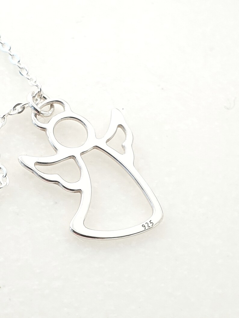 May include: Silver angel pendant necklace with a delicate outline design. The pendant has a 925 stamp on the back.