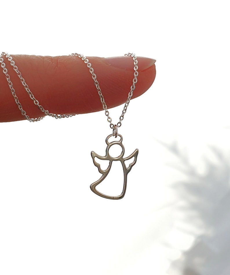 May include: A silver chain necklace with a delicate angel pendant. The angel is outlined in silver and has a halo.