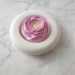 Könnte beinhalten: Weiße Silikonform in Form einer Blume mit einer rosa und weißen Blume im Inneren.