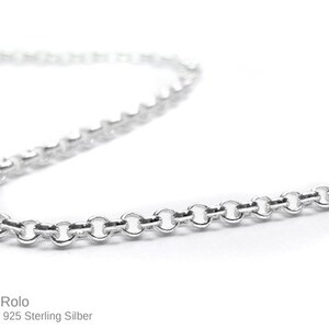 May include: A close-up of a silver Rolo chain necklace. The chain is made of small, round links and is displayed against a white background. The text "Rolo Gliederkette 925 Sterling Silber" is at the bottom.