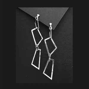 Könnte beinhalten: Ein Paar silberne geometrische Ohrhänger mit Clipverschluss. Die Ohrringe haben zwei verbundene Diamantenformen.