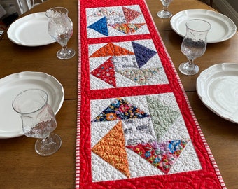 Quilted red table runner in classic color scheme of red, blue,orange, & white floral fabrics, quilted  border flying geese block centerpiece