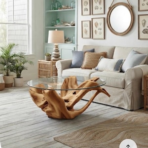 May include: A coffee table featuring a circular glass top supported by a natural, light-colored wooden tree root base. The base is crafted from a single piece of organic, gnarled wood that provides a stable foundation for the transparent glass surface.
