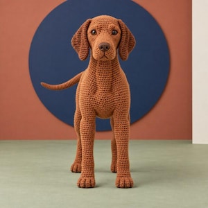 Puede incluir: Una figura de perro de pie hecha de hilo marrón mediante una técnica de ganchillo. El perro presenta orejas caídas, una nariz marrón oscura y ojos oscuros. La textura del hilo es visible en todo el cuerpo, mostrando el trabajo de punto.