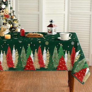 May include: A rectangular dark green tablecloth featuring a repeating pattern of stylized Christmas trees in red, white, and gold, accented with small stars and snowflakes. The table is set with a wooden serving board, a white lantern, and a teacup.