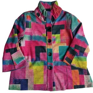May include: A long-sleeve jacket featuring a vibrant, multi-colored geometric pattern in shades of pink, yellow, blue, and black. The jacket has a high collar, a front button closure with four dark buttons, and a textured herringbone weave fabric.