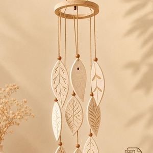 May include: A hanging mobile featuring a circular wooden frame with multiple strings suspended from it. Each string holds a textured, light-colored clay leaf ornament and small wooden beads. The text reads Hanging Bells Template and Printable Template.