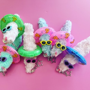 May include: Six plush toys shaped like worms wearing colorful inflatable pool floats and sunglasses. Each worm has a different color float and sunglasses.