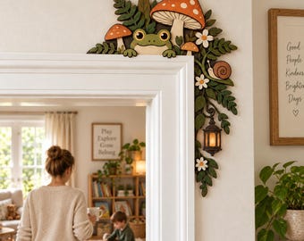 Può includere: Una decorazione in legno per l'angolo del telaio della porta raffigurante una rana verde, funghi arancioni e bianchi, foglie verdi, una piccola lumaca e una lanterna sospesa. L'oggetto è progettato per l'angolo superiore del telaio.