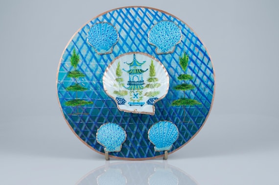 A one-of-a-kind mixed-media round art piece combining shells and hand-painting into a striking pagoda scene — the definition of 'a real person made this and there's only one in the world'.