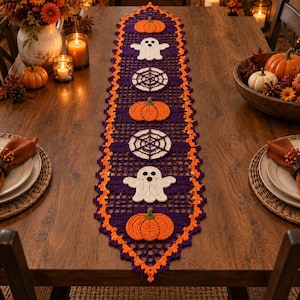 Peut inclure: Un long chemin de table en crochet rectangulaire de couleur violet foncé avec une bordure festonnée orange vif. Le chemin de table présente des appliqués répétitifs de fantômes blancs, de toiles d'araignées et de citrouilles orange.