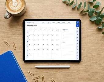 May include: A digital tablet displaying a January 2027 calendar interface with a monthly focus and notes section. The screen shows the text Nuvox, January 2027, and various navigation tabs. The tablet is positioned on a wooden surface.