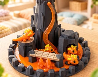 May include: A 3D printed black volcano model featuring a translucent orange lava flow, a wooden-style bridge, and several small orange creatures with yellow spikes positioned around the base and inside a cave-like structure.