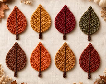 May include: Eight crocheted leaf appliques arranged in two rows. The leaves feature textured yarn stitches in autumn colors including orange, yellow, deep red, dark green, and brown. Each leaf has a central stem and a pointed tip design.