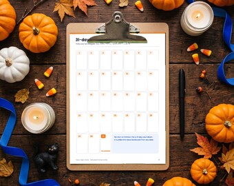 May include: A 31-day calendar sheet on a metal clipboard, featuring a grid for daily tasks, surrounded by orange pumpkins, white pumpkins, autumn leaves, two candles, a black cat figurine, a black pen, and candy corn pieces.