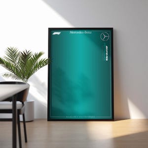Puede incluir: Un póster rectangular enmarcado con un fondo degradado en color verde azulado, el logotipo de Mercedes-Benz, el logotipo de F1 y el texto Mercedes-AMG PETRONAS Formula One Team y Mercedes-AMG F1 W14 E PERFORMANCE en blanco.