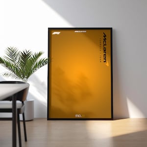 May include: A vertical rectangular poster in a black frame featuring a gradient orange background. The text McLaren Formula 1 Team is printed vertically on the right side. The F1 logo is in the top left, and MCL39 is at the bottom center.