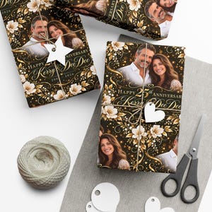 Könnte beinhalten: Personalisiertes Geschenkpapier mit schwarzem Hintergrund, goldenen Blumenornamenten, weißen Blüten und einem Foto eines Paares. Der Text lautet Happy 25th Anniversary Kerry & Dee Dee 2001-2026. Das Papier ist mit Kordel und weißen Geschenkanhängern versehen.
