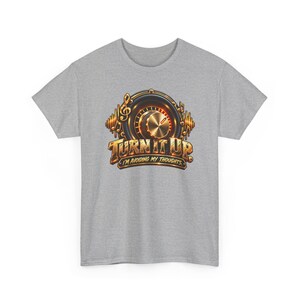 May include: A heather gray t-shirt featuring a graphic of a gold and black volume knob surrounded by musical notes. The text "TURN IT UP" appears in large gold letters above the smaller text "I'M AVOIDING MY THOUGHTS" in a banner.