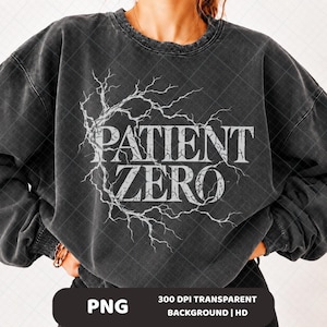Puede incluir: Una sudadera de cuello redondo en gris carbón con un gráfico blanco desgastado de ramas de árbol o rayos que forman un marco circular alrededor del texto PATIENT ZERO en una fuente serif negrita. La prenda tiene una textura lavada.