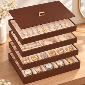 May include: A multi-tiered brown jewelry organizer box with a removable lid. The interior features cream-colored velvet lining with compartments for necklaces, rings, earrings, and wristwatches. The top tray displays various gold-toned pendants.
