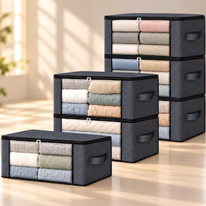 May include: A set of four rectangular dark gray fabric storage bins with clear plastic front windows and zippered closures. Each bin features side handles and is filled with neatly folded textiles in various neutral and pastel colors.