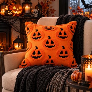 May include: A square throw pillow in bright orange featuring a repeating pattern of black jack-o'-lantern faces. The pillow has a textured, tufted surface with raised pumpkin designs and a soft, knit-like appearance throughout the fabric.