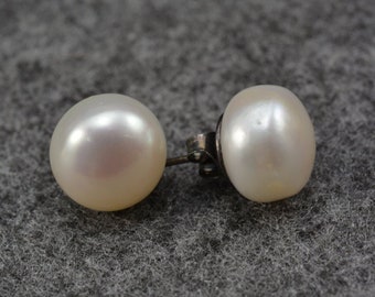 Puede incluir: Un par de pendientes de perlas con postes de plata. Las perlas son blancas y redondas.
