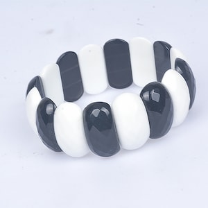 May include: Black and white stretchy bracelet made of oval-shaped beads.