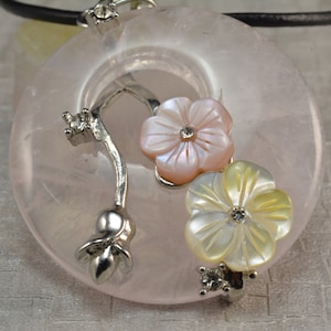 May include: A pink rose quartz pendant necklace with a silver chain and two white and pink shell flower accents.
