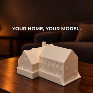 May include: A white 3D printed architectural model of a house with a gabled roof and multiple windows. The text "YOUR HOME, YOUR MODEL." is printed in white above the model. The structure features a central chimney and a rectangular base.