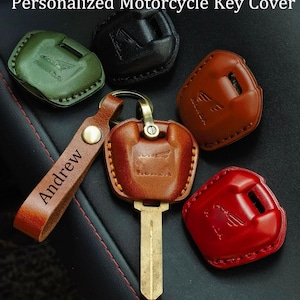 May include: A collection of leather motorcycle key covers in green, black, brown, and red, each featuring a Honda logo. One brown cover is attached to a metal key and a leather keychain strap with the name Andrew embossed in black text.