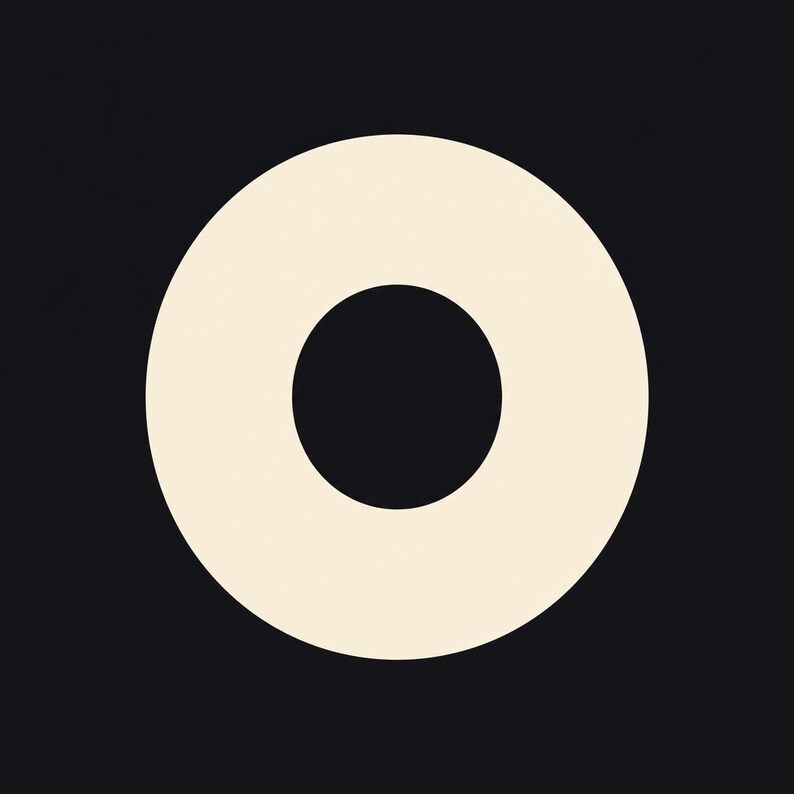 May include: A graphic design featuring a large, solid, off-white circle centered on a plain black background. The circle has a smaller, solid black circular cutout in its exact center, creating a ring or donut shape with clean, sharp edges.