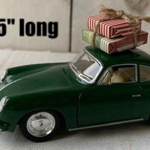 May include: A green toy car with a stack of wrapped gifts on the roof. The car is 5 inches long.