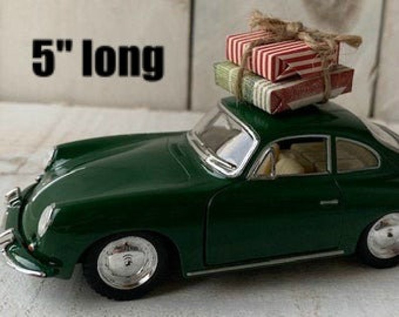 May include: A green toy car with a stack of wrapped gifts on the roof. The car is 5 inches long.
