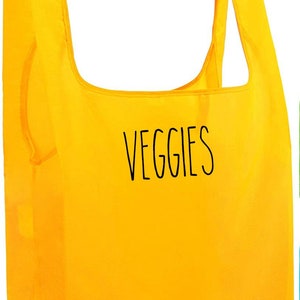May include: A bright yellow reusable grocery bag with the word "VEGGIES" printed in black on the front.