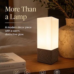 May include: A rectangular table lamp with a white frosted glass shade and a textured, perforated base. The lamp emits a warm, soft glow. Text on the image reads: More Than a Lamp, A modern décor piece with a warm, distinctive glow, Modern Design, Warm Glow, Perfect for Any Space, Great Gift Idea.