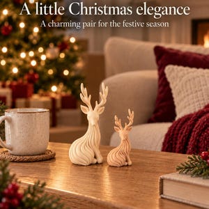 May include: Two cream-colored deer figurines with stylized, flowing lines and branched antlers. The text "A little Christmas elegance" and "A charming pair for the festive season" is printed above the deer on the image.