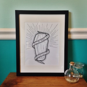 May include: Black and white illustration of a coffin with the text "Tell me where did you sleep last night" printed on a white background. The illustration is framed in a black frame.