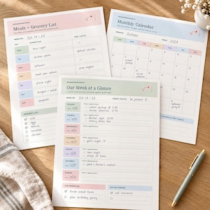 May include: Three white paper planners with pastel-coloured accents and handwritten text. The sheets include a Meals and Grocery List, a Monthly Calendar for October 2024, and an Our Week at a Glance schedule. A silver pen rests on the side.