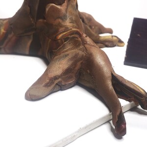 Puede incluir: Una escultura de arcilla marr&oacute;n y beige de un tronco de &aacute;rbol con m&uacute;ltiples ramas. La escultura tiene un aspecto marmoleado y descansa sobre una superficie blanca.