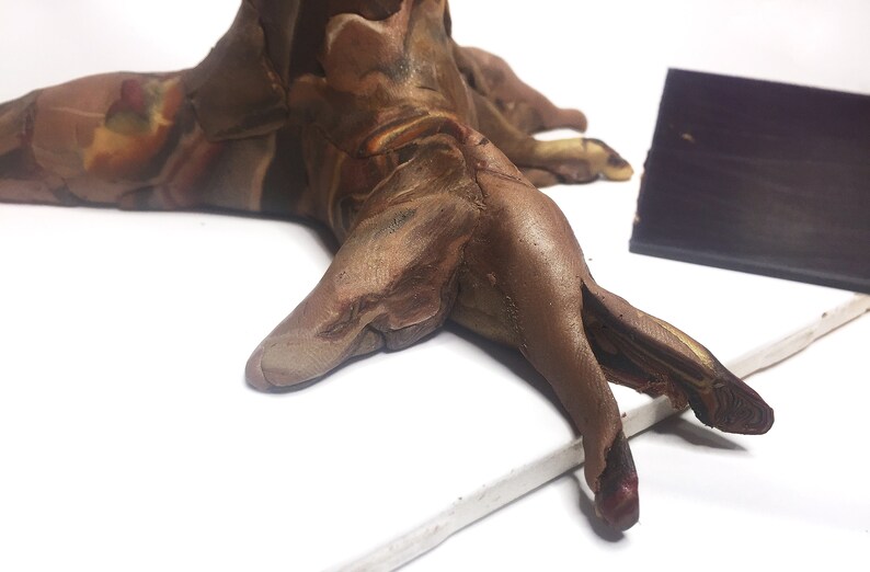 Puede incluir: Una escultura de arcilla marr&oacute;n y beige de un tronco de &aacute;rbol con m&uacute;ltiples ramas. La escultura tiene un aspecto marmoleado y descansa sobre una superficie blanca.