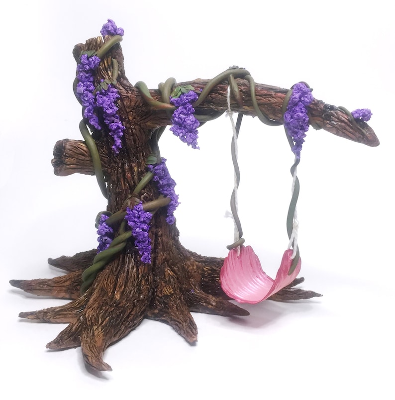 Puede incluir: Un &aacute;rbol en miniatura con un columpio rosa colgando de una rama. El &aacute;rbol est&aacute; decorado con flores y enredaderas moradas.