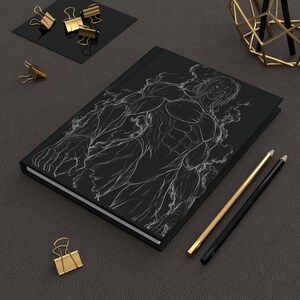 May include: A black hardback notebook featuring a white line art illustration of a muscular, humanoid figure surrounded by wispy smoke effects. The notebook is accompanied by a gold pencil, a black pencil, and several gold metal binder clips.